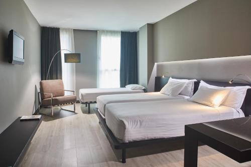 una habitación de hotel con 2 camas y una silla en Silken Gran Teatro en Burgos
