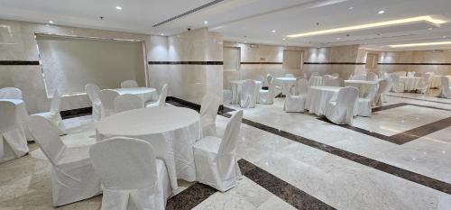 EWG Al Mashaer Hotel في مكة المكرمة: قاعة اجتماعات مع طاولات بيضاء وكراسي بيضاء