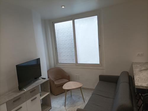 - un salon avec un canapé, une télévision et une chaise dans l'établissement Appartement 3p, à Nice