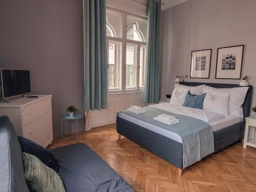 a bedroom with a large bed and a couch at Mikszáth Apartments Budapest in Budapest