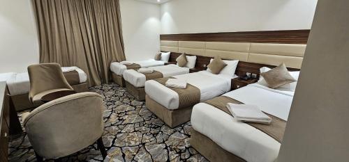 a hotel room with four beds and a chair at EWG Al Mashaer Hotel in Makkah