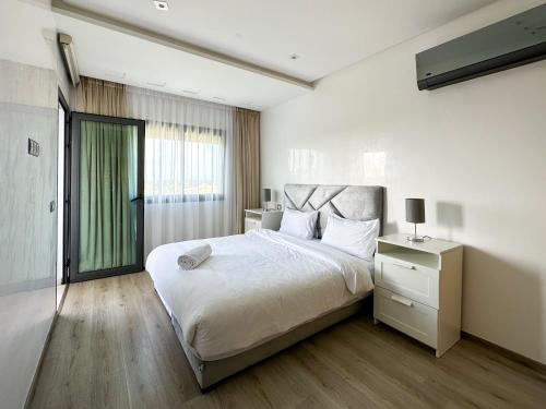 ein Schlafzimmer mit einem großen weißen Bett und einem Fenster in der Unterkunft luxe appartement met zeezicht en zwembad Mohammedia Parc in Mohammedia