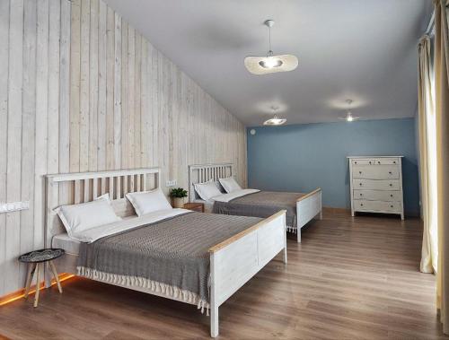 HYGGE HOME уютный коттедж с террасой и баней для проживания нескольких семей في Besqaynar: سريرين في غرفة نوم بجدران زرقاء وأرضيات خشبية