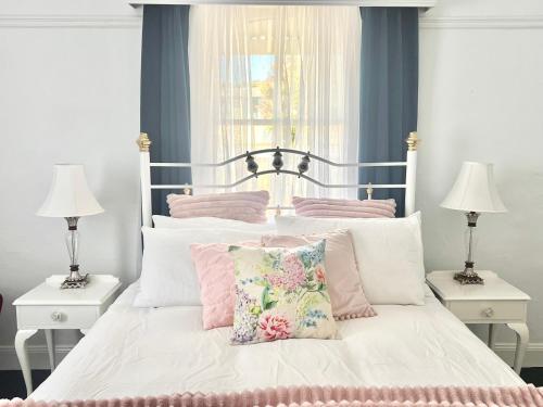a bedroom with a bed with pink and white pillows at 1880 Cottage in Tumut
