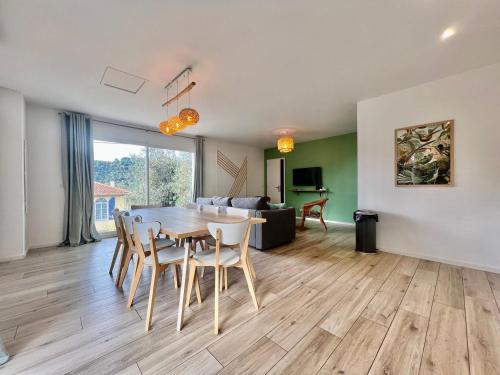 a dining room and living room with a table and chairs at Évasion Tranquille à 20 min de Nice in Contes