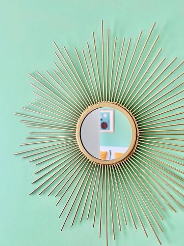 a gold sunburst mirror on a blue wall at Évasion Tranquille à 20 min de Nice in Contes