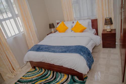 1 dormitorio con 1 cama con almohadas de color naranja y azul en Sisi's Homes, en Arusha