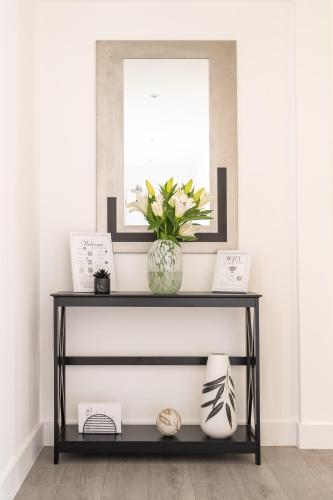 a black and white console table with a vase of flowers at Oasis at Hemel Hempstead in Hemel Hempstead