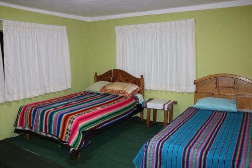 2 camas en una habitación con paredes y ventanas verdes en SUNSET Lodge Amantani, en Ocosuyo