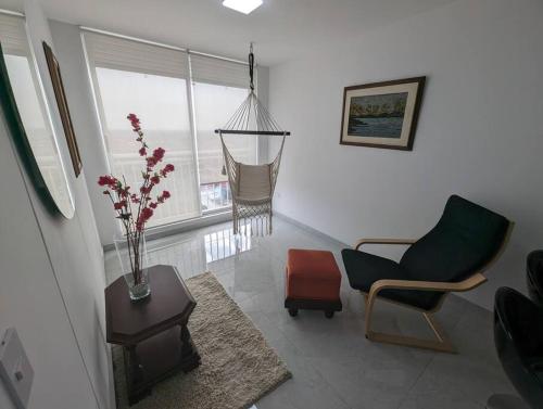 a living room with a chair and a vase of flowers at Lindo apartamento en el centro in Cali