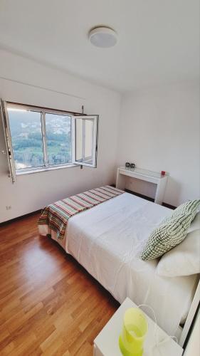 a white bedroom with a bed and a table at Retiro do Viajante in Penacova