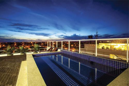 um edifício com piscina no telhado à noite em Malibu Plaza Hotel em Lauro de Freitas