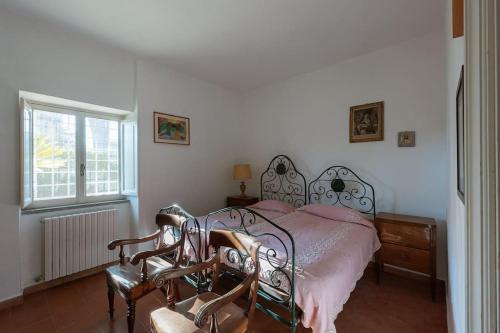 ManzianaにあるVilla Cicasのベッドと椅子2脚と窓のある寝室