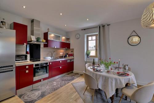 une cuisine avec des placards rouges et une table avec des chaises dans l'établissement Appartement 1 chambre L'ANSE MORGANE, à Dinard