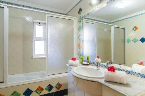 uma casa de banho com um lavatório e um espelho grande em Vilamoura Charming Modern Condominium em Quarteira