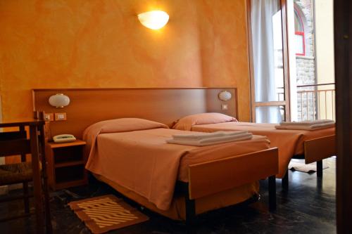 two beds in a room with orange walls at Hotel Corallo in Moneglia