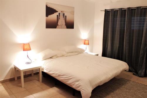um quarto com uma cama e 2 candeeiros nas mesas em Vilamoura Charming Modern Condominium em Quarteira