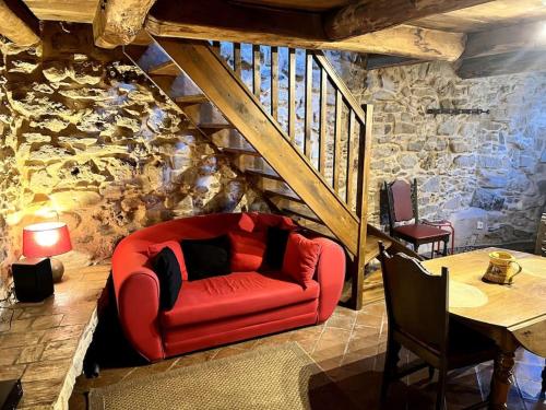 a red couch in a living room with a stone wall at La Maison De Blanche Neige in Assignan