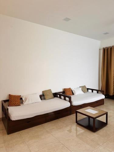 two beds in a room with a coffee table at Teak Stays in Prayagraj