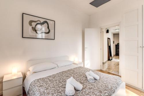 a white bedroom with a bed and two white towels at V E N E R E Apartments in Rome