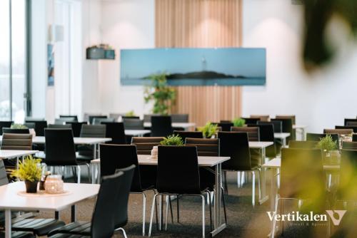 una sala da pranzo con tavoli, sedie e schermo per proiezione di Vertikalen a Lillesand