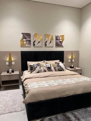 a bedroom with a large bed with paintings on the wall at Elite Apartment 3 in Riyadh