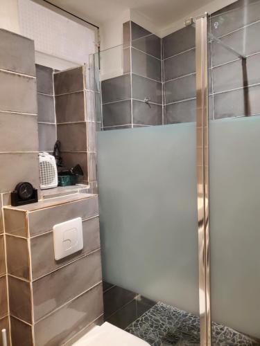 une douche avec une porte vitrée dans une salle de bain dans l'établissement T3 Provençal à la Ciotat, à La Ciotat
