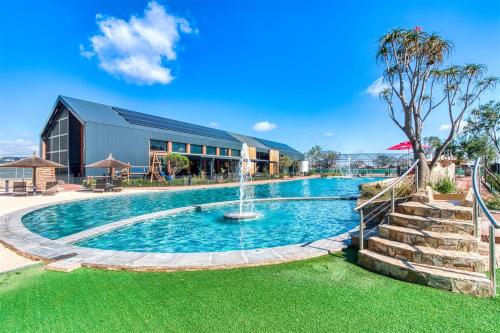 a pool with a fountain in front of a building at The Lagoon Exquisite Apartments in Pretoria