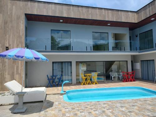 a house with a swimming pool and an umbrella at Morada Stucchi in Balneário Camboriú