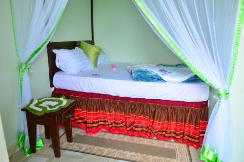 a bedroom with a canopy bed with a table at Zion Camp in Entebbe