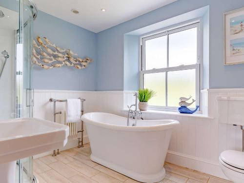 a bathroom with a white tub and a window at 4 Bed in Looe 82662 in Lanreath