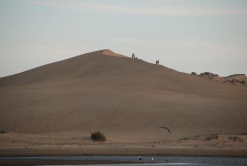 a hill in the desert with people on top of it at Complejo Sol de Valizas in Barra de Valizas