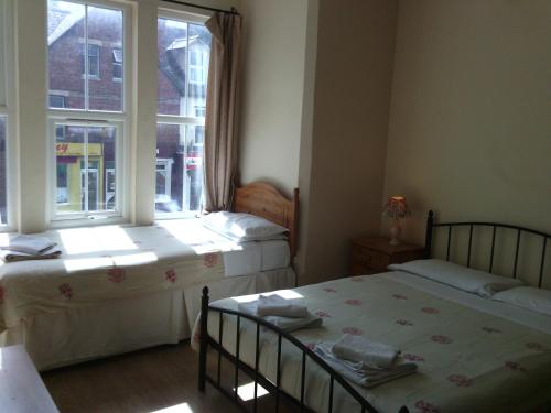 two beds in a room with a window at Amazon Guest House in Oxford