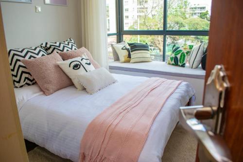 Laurel Hill-Suites في نيروبي: غرفة نوم بها سرير مع وسائد ونافذة