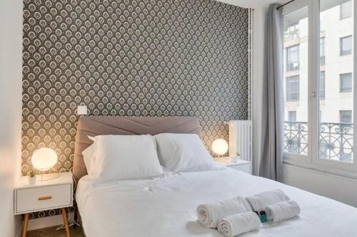una camera da letto con un grande letto bianco e una grande finestra di Appartement cosy proche Arc de Triomphe - 4P a Parigi