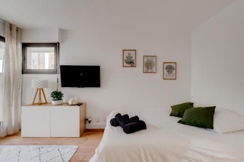 une chambre blanche avec un lit et une télévision à écran plat dans l'établissement Studio Place Dupuy, clim, parking, terrasse, à Toulouse