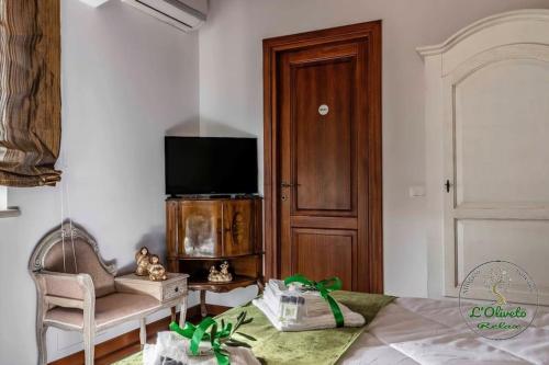 a room with a tv and a chair and a table at Oliveto Relax Alloggio Turistico in Rome