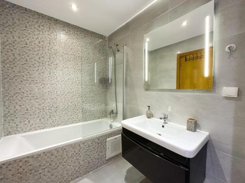 bagno con lavandino, vasca e specchio di luxe appartement met zeezicht en zwembad Mohammedia Parc a Mohammedia