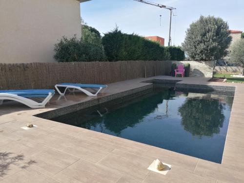 - une piscine dans un jardin avec 2 chaises longues et une chaise rose dans l'établissement F2 Blanc Bleu, à Sainte-Marie-la-Mer