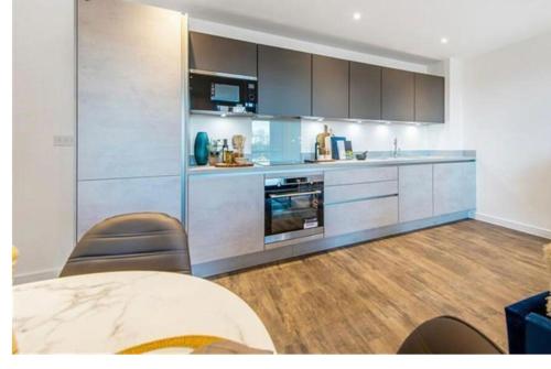 a kitchen with stainless steel appliances and wooden floors at UPPAMOST luxury home 3 in Dagenham
