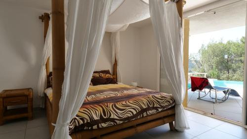 - une chambre avec un lit à baldaquin et un balcon dans l'établissement Villa d'Eden domaineleshesperides, à Bagnols-en-Forêt