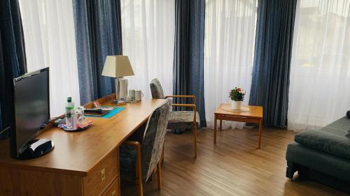 ein Wohnzimmer mit einem Schreibtisch, einem TV und einem Sofa in der Unterkunft Hotel Garni in Rosbach vor der Höhe