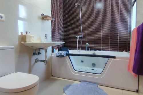 een badkamer met een bad, een toilet en een wastafel bij Apartamento Deluxe: hidromasaje, terraza y vistas. in Las Hortichuelas