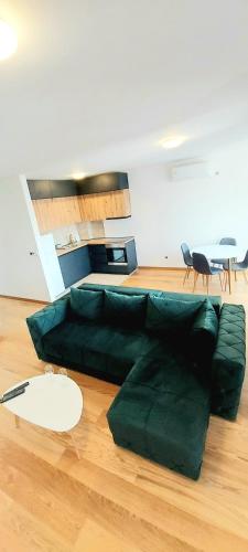 a green couch sitting on a wooden floor in a living room at Magenta Zvezdara in Belgrade