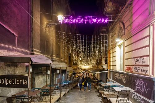 a group of people walking down a street at night at FilHome 44 in Catania