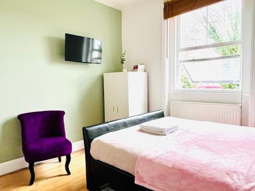 a bedroom with a bed and a purple chair at Gorgeous Studio 15 Minutes from Central London in London