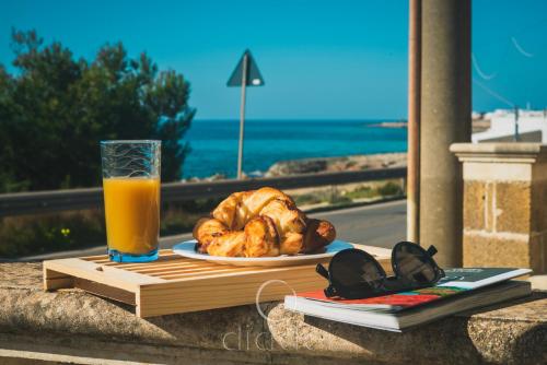 einen Tisch mit einem Teller Brot und einem Glas Orangensaft in der Unterkunft Oasi Marina Apartment Sea View by Diddoi in Torre Suda