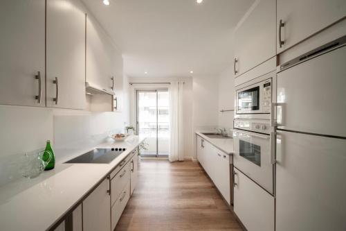Il comprend une cuisine blanche avec des placards blancs et du parquet. dans l'établissement REF 1933 - Cannes - Apartment for rent, à Cannes