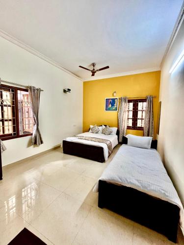 two beds in a bedroom with yellow walls at The Ruby Park in Yelagiri