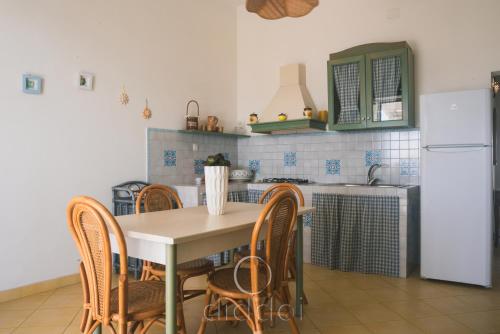 eine Küche mit einem Tisch und Stühlen sowie einem Kühlschrank in der Unterkunft Oasi Marina Apartment Sea View by Diddoi in Torre Suda